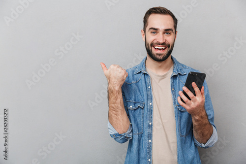 Excited cheerful man wearing shirt standing isolated