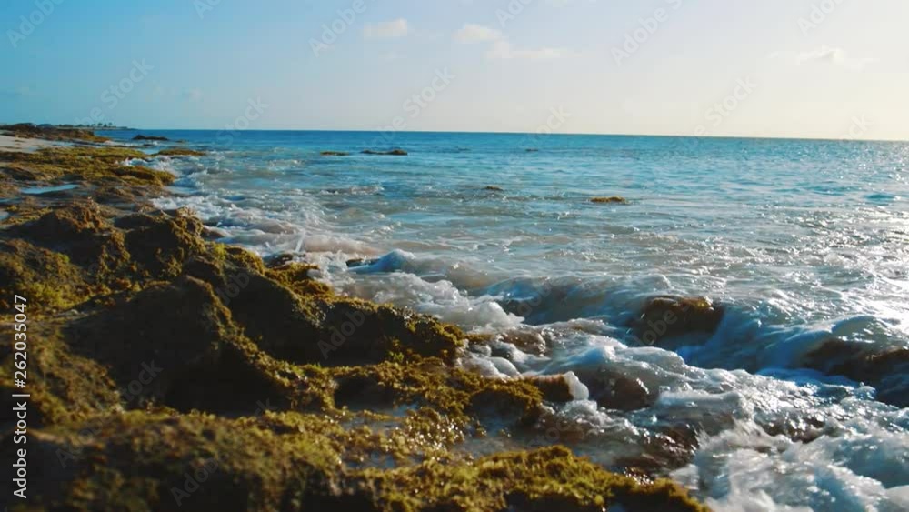 Slow motion parallax shot of small waves gently crashing into a rocky shoreline on a beach in Bonaire, Caribbean Slow motion parallax shot of small waves gently crashing into a rocky shoreline on a beach in Bonaire, Caribbean