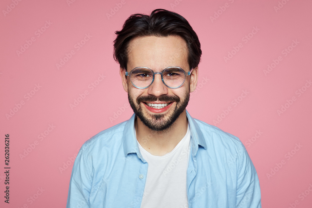 Attractive hipster male smiling at camera, glad to find suitable well paid job, isolated over pink background. Attractive hipster male smiling at camera, glad to find suitable well paid job, isolated over pink background.