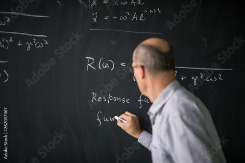 Math teacher drawing   fuction graph on a blackboard during mathclass (shallow DOF, color toned image)