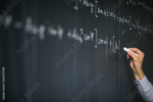 Fotografi Math teacher by the blackboard during mathclass - detail of the hand with chalk