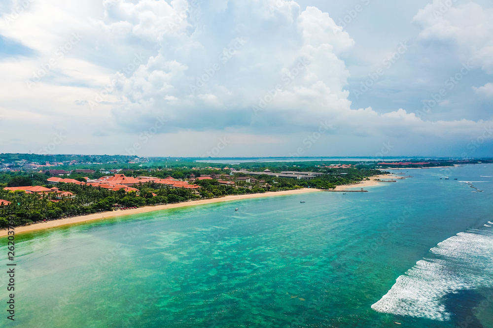 Aerial view of Nusa Dua Beach in Bali Indonesia with waves and a turquoise sea taken above from the sea during spring with a drone