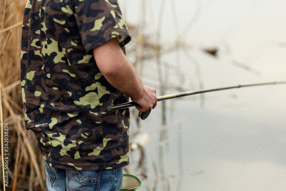fisherman catches fish by the river. Man holds fishing pole