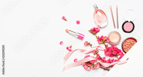 Different makeup cosmetic. Ball blush rouge lipstick concealer bottle of perfume makeup brush spring pink flowers in white gift package on light background top view flat lay. Beauty fashion background