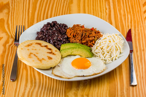 Venezuelan breakfast of arepa, fried egg, black beans, mechada meat, white cheese and avocado photo