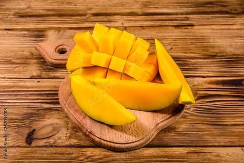 Cutting board with chopped mango fruit on a wooden table