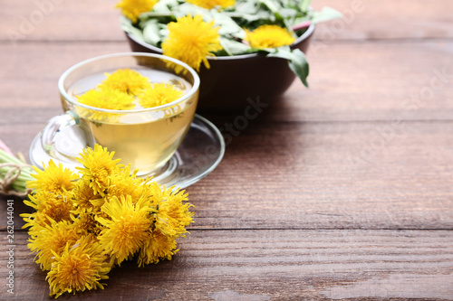 Yellow dandelions with cup of tea on brown wooden table