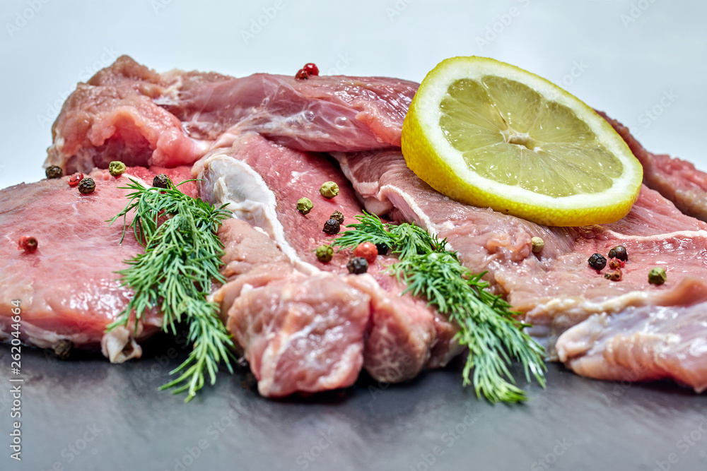 Raw fresh beef meat with a sprig of dill and lemon on a black background