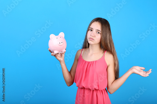 Young girl holding pink piggybank on blue background