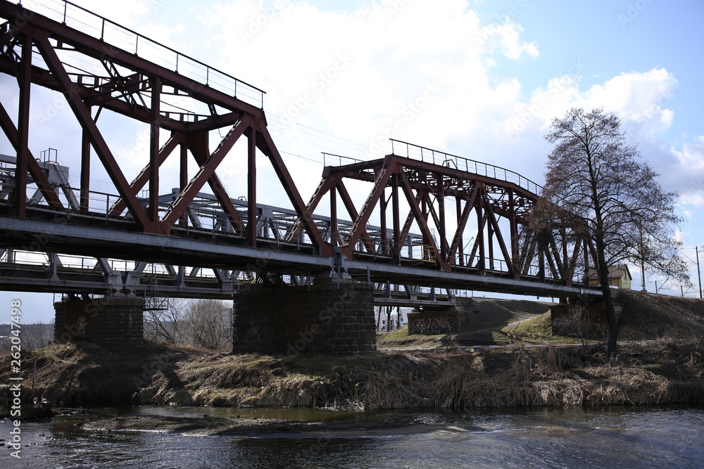Metallic railway bridge over the river with a fast flow.