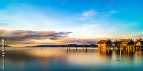 Das Pfahlbautenmuseum am Bodensee	im Sonnenuntergang mit bunter Wolkenstimmung  photo