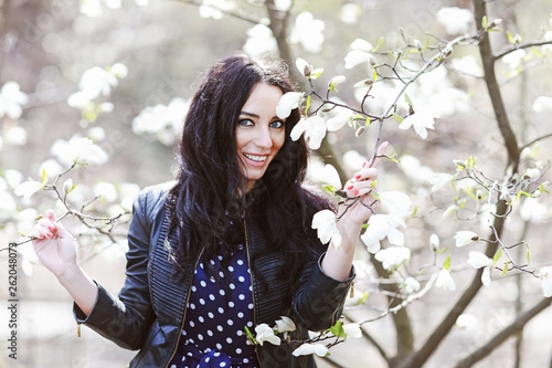 beautiful brunette woman in a blue dress and a knitted bag near magnolia blooming © prohor08