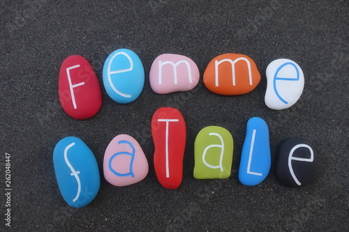 Femme fatale text composed with painted sea stones over black volcanic sand