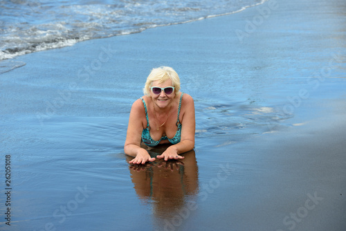 Mature aged woman on wet black sand of Arena beach.