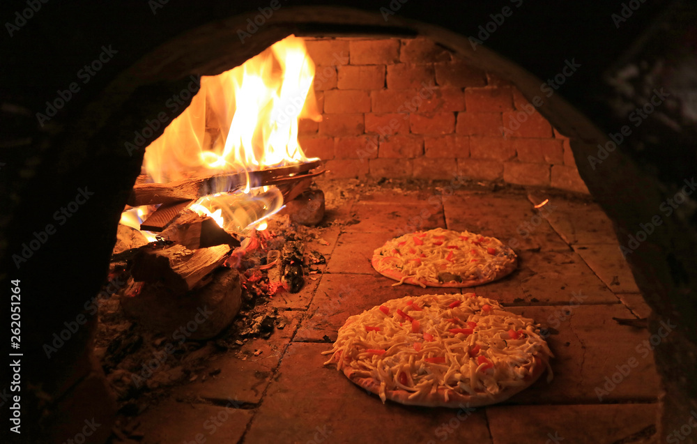 Pizzas Topped with Cheese and Tomato Being Baked in the Wood Fired Oven