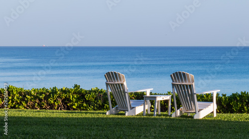 White chairs in front of the Atlantic Ocean reflecting the bright sunlight of the morning sun. Nassau, The Bahamas.