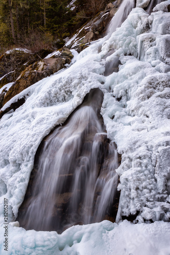 Beautiful view of a waterfall, Crooked Falls, covered in melting ice during springtime. Taken near Squamish, North of Vancouver, BC, Canada.