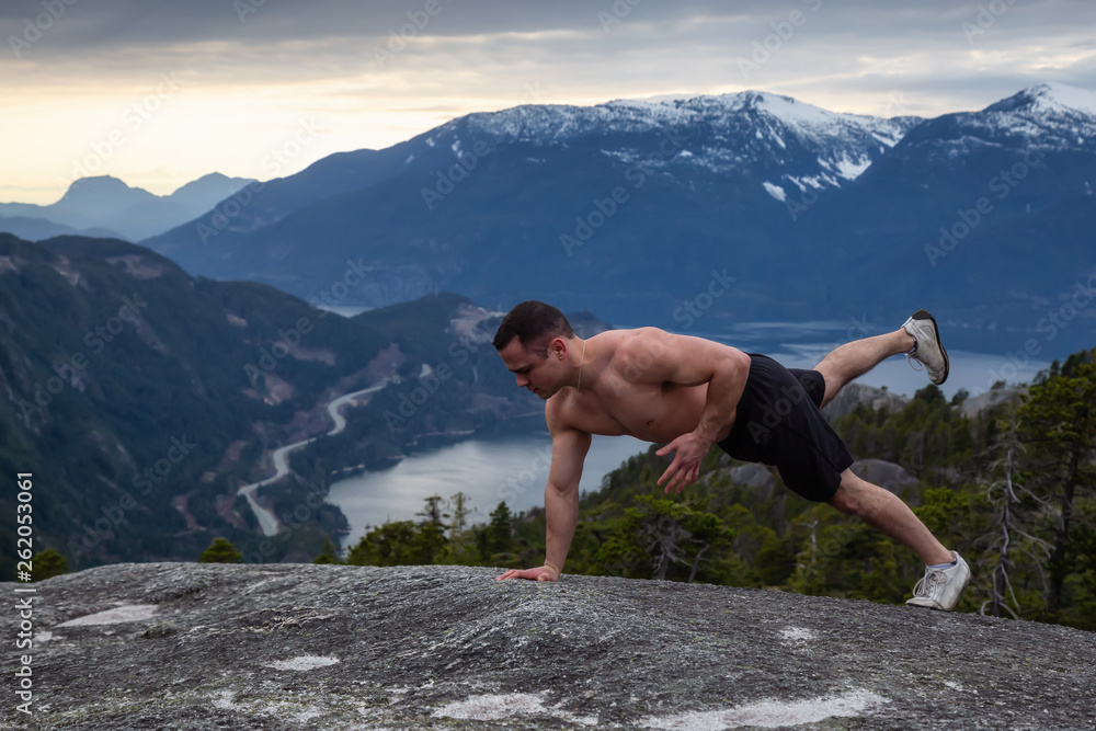 Fit and Muscular Young Man is doing exercises on top of the Mountain during a cloudy sunset. Taken on Chief Mountain in Squamish, North of Vancouver, BC, Canada. Fit and Muscular Young Man is doing exercises on top of the Mountain during a cloudy sunset. Taken on Chief Mountain in Squamish, North of Vancouver, BC, Canada.