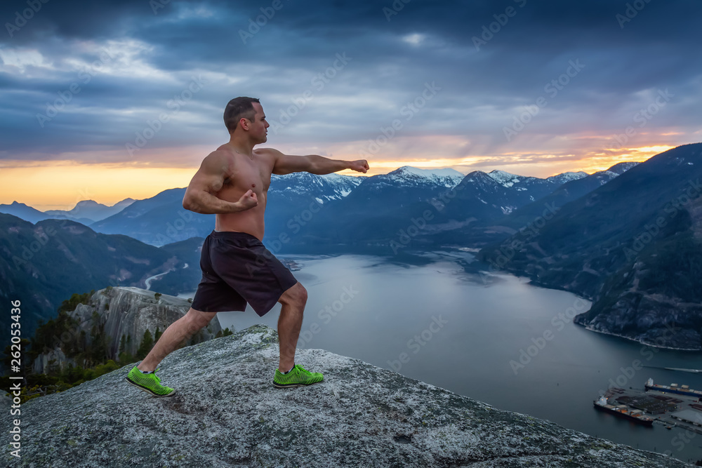 Fit and Muscular Young Man is practicing martial arts on top of the Mountain during a colorful sunset. Taken on Chief Mountain in Squamish, North of Vancouver, BC, Canada.