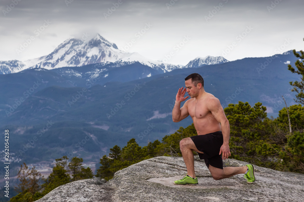 Fit and Muscular Young Man is doing exercises on top of the Mountain during a cloudy day. Taken on Chief Mountain in Squamish, North of Vancouver, BC, Canada. Fit and Muscular Young Man is doing exercises on top of the Mountain during a cloudy day. Taken on Chief Mountain in Squamish, North of Vancouver, BC, Canada.