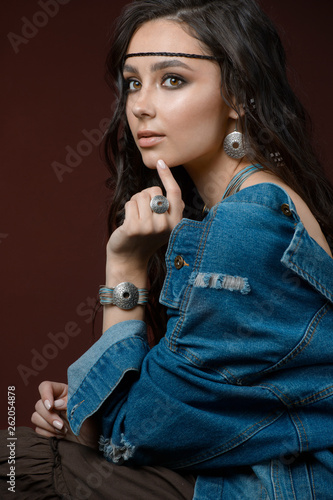 Stylish girl shows silver jewelry and accessories. Studio portrait isolated on a brown background