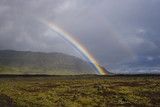 rainbow over field with blue sky and clouds in Iceland