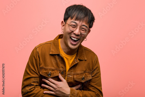 Young chinese man wearing a jacket laughing and having fun photo