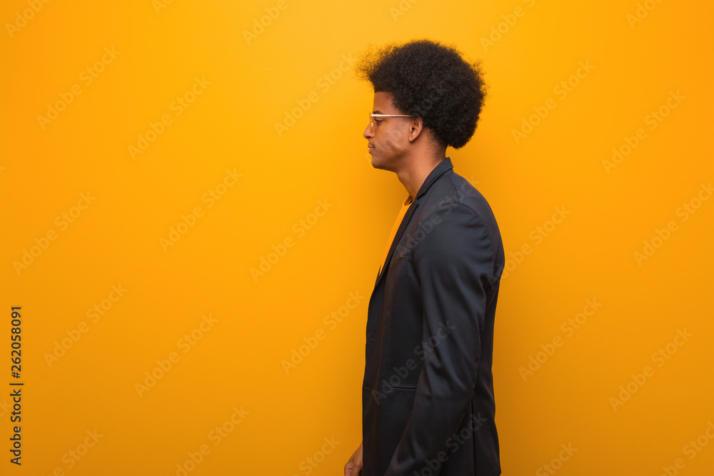 Obraz premium Young business african american man over an orange wall on the side looking to front