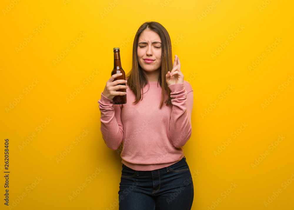 Young cute woman holding a beer crossing fingers for having luck Young cute woman holding a beer crossing fingers for having luck