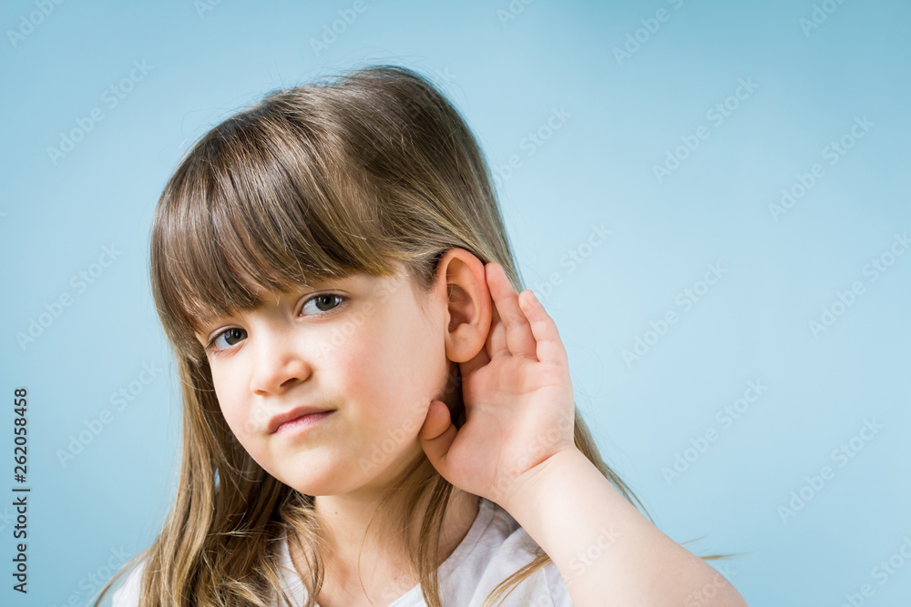 Toddler girl with hearing problem on light blue background. Close up, copy space. Toddler girl with hearing problem on light blue background. Close up, copy space.