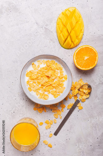 Breakfast which consist of different yellow ingredients - sereales and fruits. Gray background