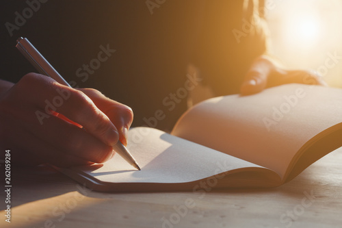 female hands writing notes on notebook with pen photo