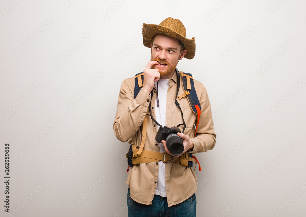 Young redhead explorer man relaxed thinking about something looking at a copy space. Holding a camera. Young redhead explorer man relaxed thinking about something looking at a copy space. Holding a camera.