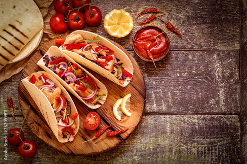 tacos  Mexican food with chicken, pepper, tomatoes, cabbage and salsa on a wooden Board