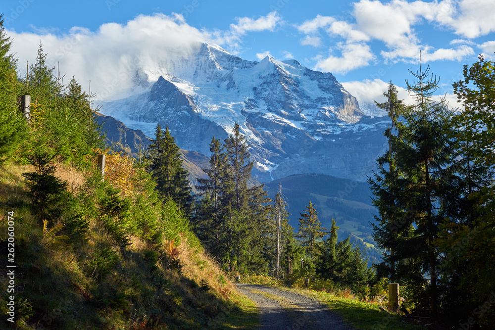 The gravel mountain road and Jungfrau peak view in the clouds near Swiss Alpine village Wengen in Switzerland.