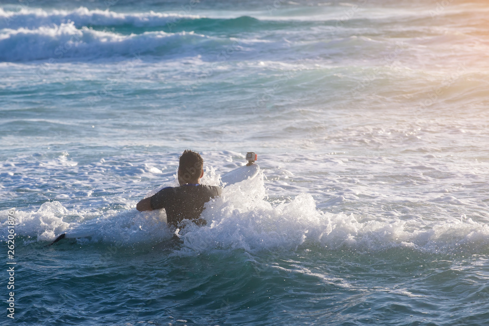 Young man, beginner Surfer learns to surf on a sea foam on the Crete island, beach Falasarna Young man, beginner Surfer learns to surf on a sea foam on the Crete island, beach Falasarna