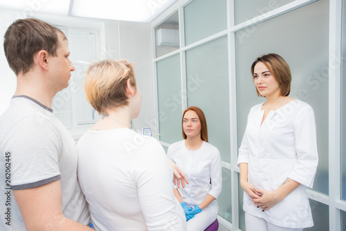 pregnant woman and her husband communicate with two young women dentists in a medical office. Dental treatment for pregnant women