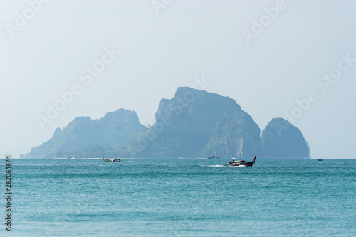 Boat sails to the sea in the turquoise waters against the rocks on the island in Asia in Thailand, in Krabi province