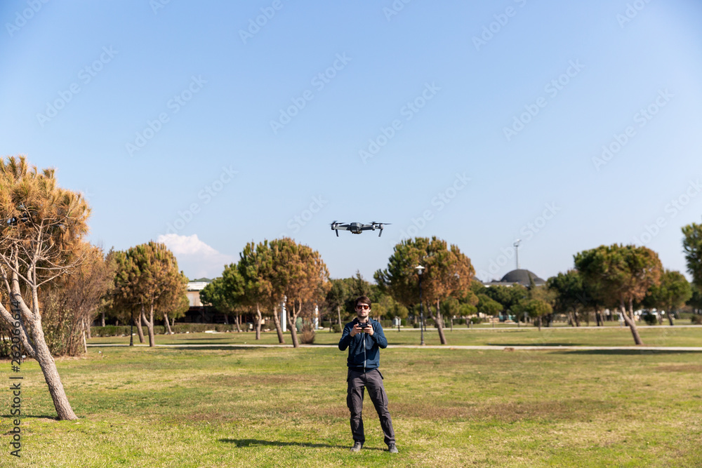 A man piloting a drone in the park in spring-summer time A man piloting a drone in the park in spring-summer time