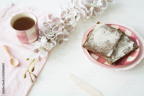 rye bread, Dutch roggebrood, on pink plate. Cup of tea, flowers and white background photo