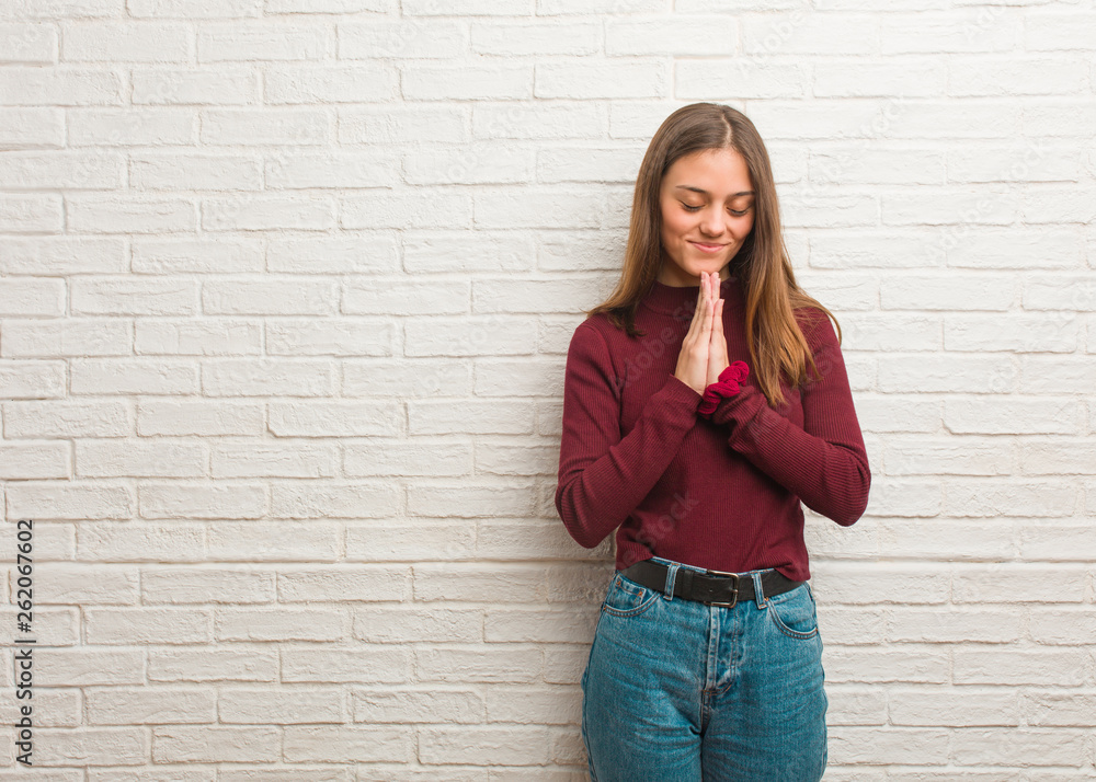Young cool woman over a bricks wall praying very happy and confident Young cool woman over a bricks wall praying very happy and confident