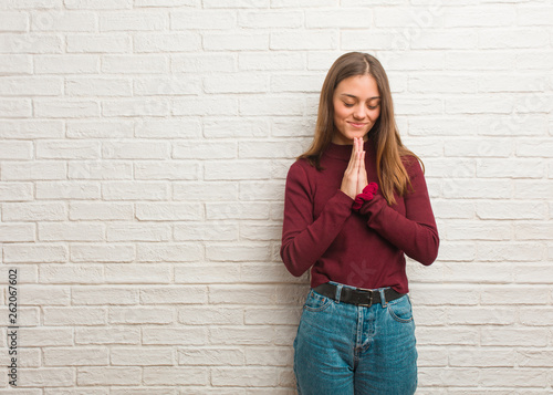 Young cool woman over a bricks wall praying very happy and confident © Asier