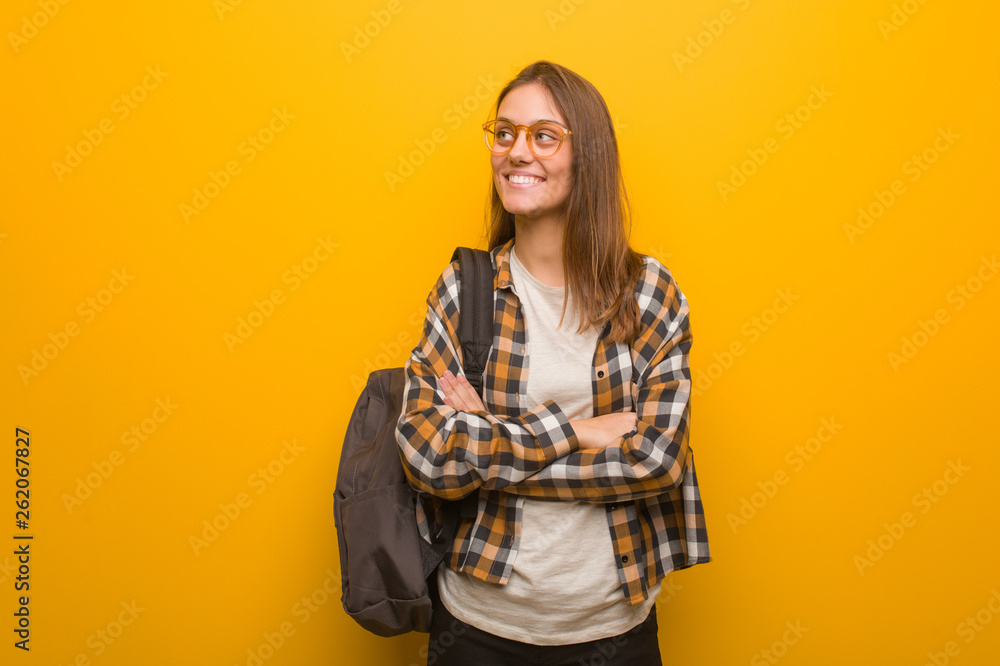 Young student woman smiling confident and crossing arms, looking up Young student woman smiling confident and crossing arms, looking up