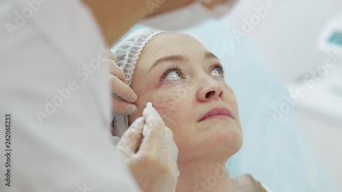 Cosmetician in gloves making face lifting injection to area around eyes. female client gets facial beauty procedure in healthcare clinic. liquid thread injection. Botox. collagen