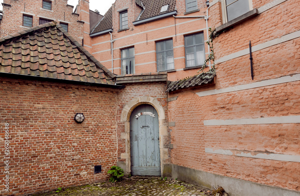 Wooden door in brick house of historical Beguinage, 13th century complex houses for beguines women