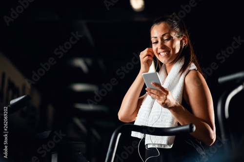 Happy female athlete enjoying in music while having sports training in a gym.