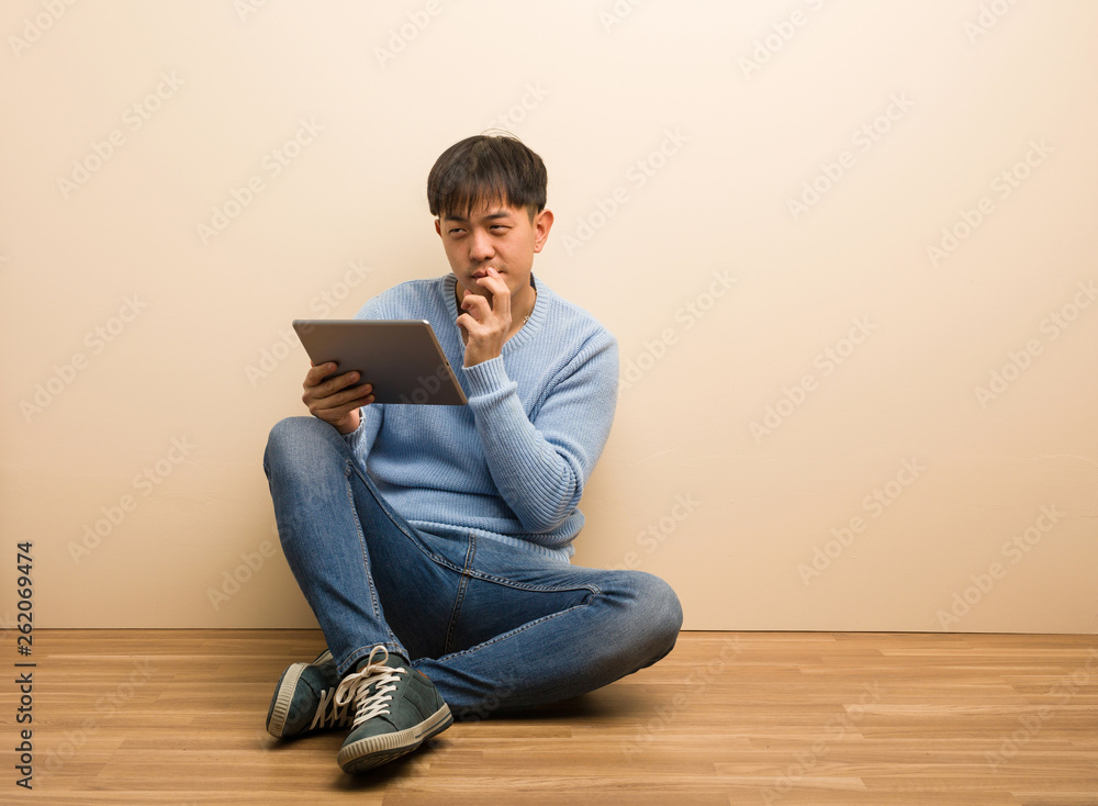 Young chinese man sitting using his tablet devising a plan