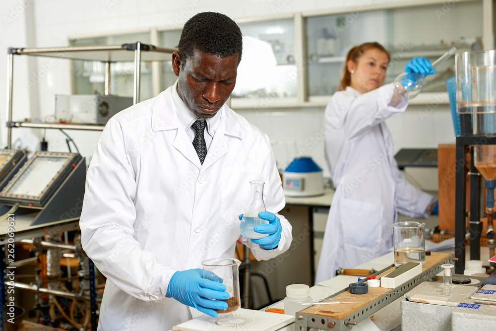 Obraz premium Serious male scientists with glass test tubes during chemical experiment
