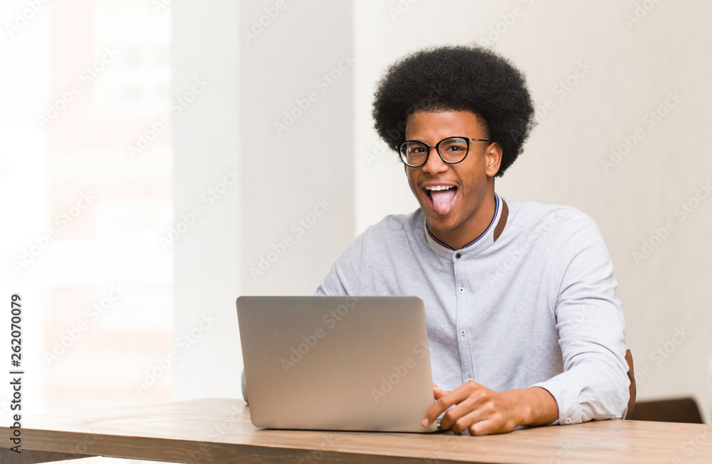 Young black man using his laptop funnny and friendly showing tongue Young black man using his laptop funnny and friendly showing tongue