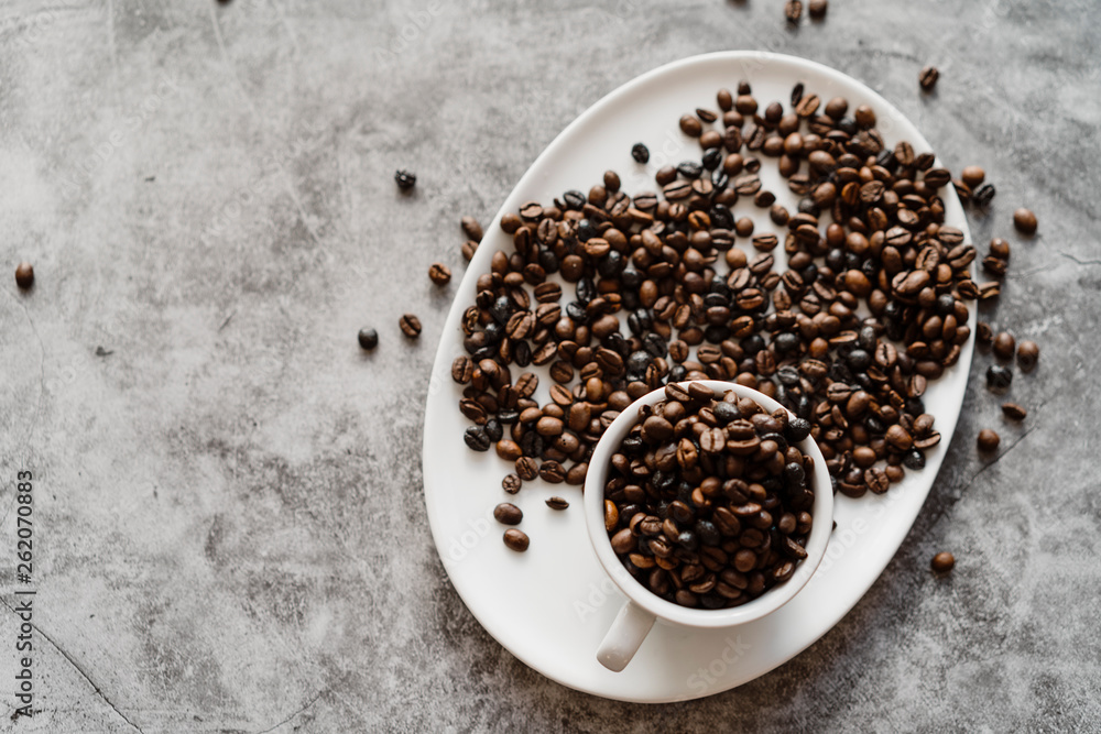 Cup full of coffee beans on white plate Cup full of coffee beans on white plate